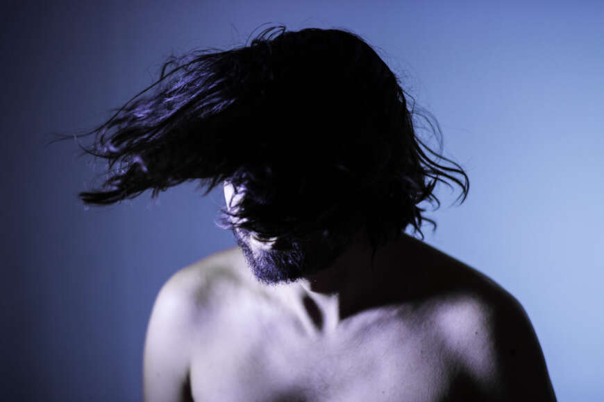 Portraitfoto Turi Agostino mit freiem Oberkörper, schüttelt die Haare vors Gesicht