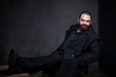 Portraitfoto Marian Gold von Alphaville, sitzend, ganz in schwarz