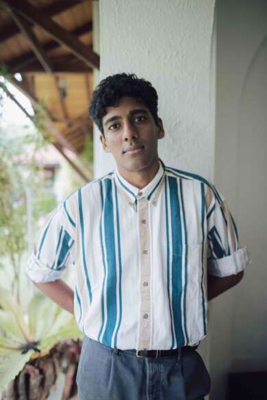 Portraitfoto Anuk Arudpragasam, die Hände hinterm Rücken verschränkt