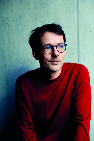 Portraitfoto Jan Böttcher, trägt rotes Langarmshirt