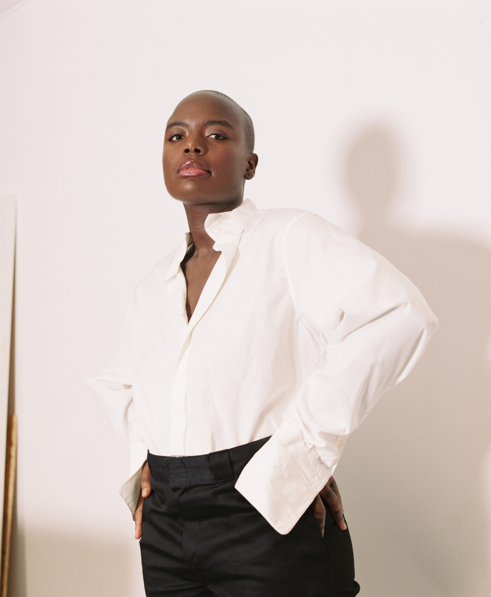 Sandra Mujinga steht im weißen Hemd vor einer Wand.