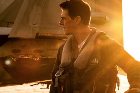 Still aus „Top Gun Maverick“: Tom Cruise steht neben einem Flugzeug, in gelbes Sonnenlicht getaucht.