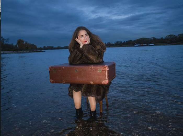 Claudia Hübbecker als Irmgard Keun sitzt auf einem Stuhl im flachem Wasser