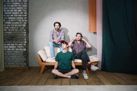 Christopher Annen, Henning May und Severin kantereit sitzen nebeneinander auf und vor dem Sofa.