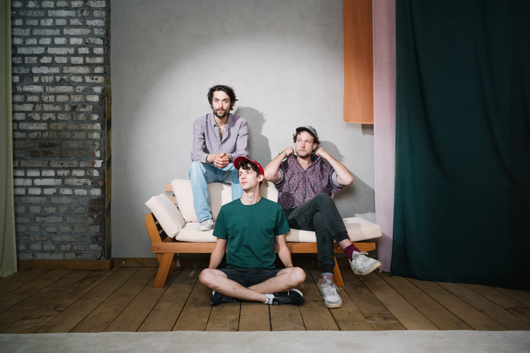 Christopher Annen, Henning May und Severin kantereit sitzen nebeneinander auf und vor dem Sofa.