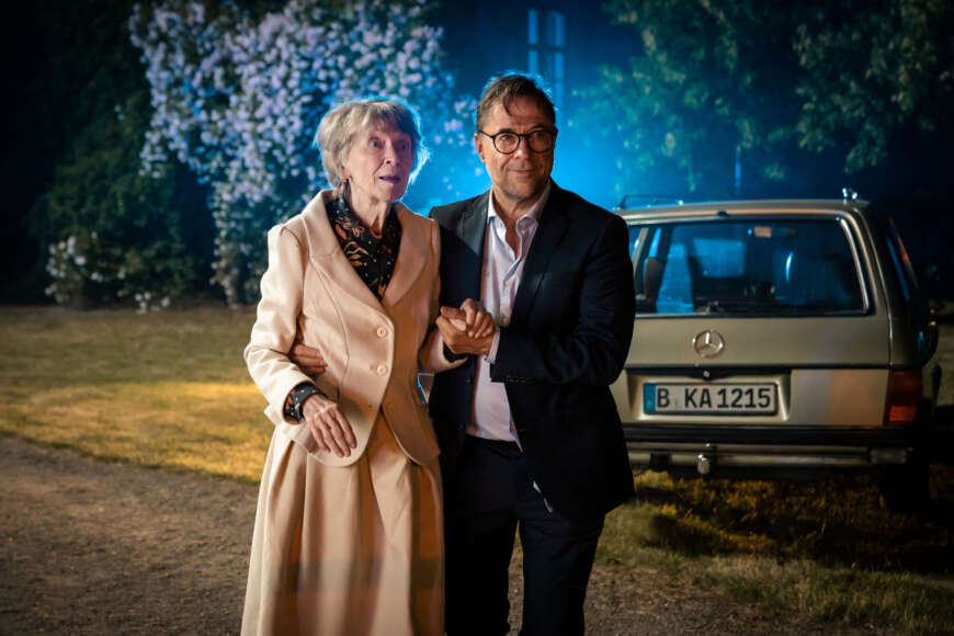 „Düstersee“: Joachim Vernau (Jan Josef Liefers) geht mit seiner Mutter Hildegard Vernau (Elisabeth Schwarz) zum Krankenwagen.
