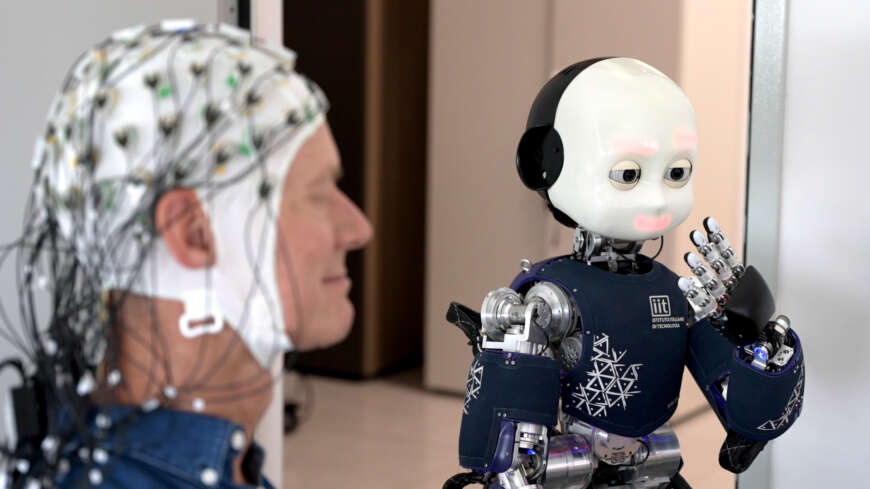 "Mein Avatar und ich - Wie KI Bewusstsein erlangt": Ingolf Baur mit einer EEG-Haube neben einem humanoiden Roboter.