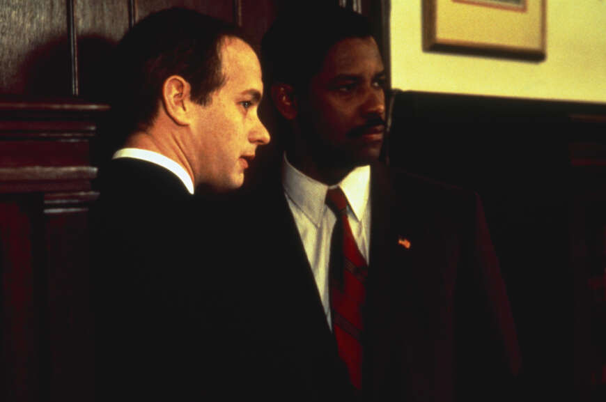 "Philadelphia": Der AIDS-kranke Andrew Beckett (Tom Hanks) und der Anwalt Joe Miller (Denzel Washington) stehen nebeneinander vor einer Holztür und haben die Köpfe zur Seite gewandt.