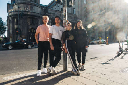 Arne Wolff, Moritz Weishaupt, Caro Sommer und Magnus Ernst stehen im Sonnenlicht auf einer Straße.
