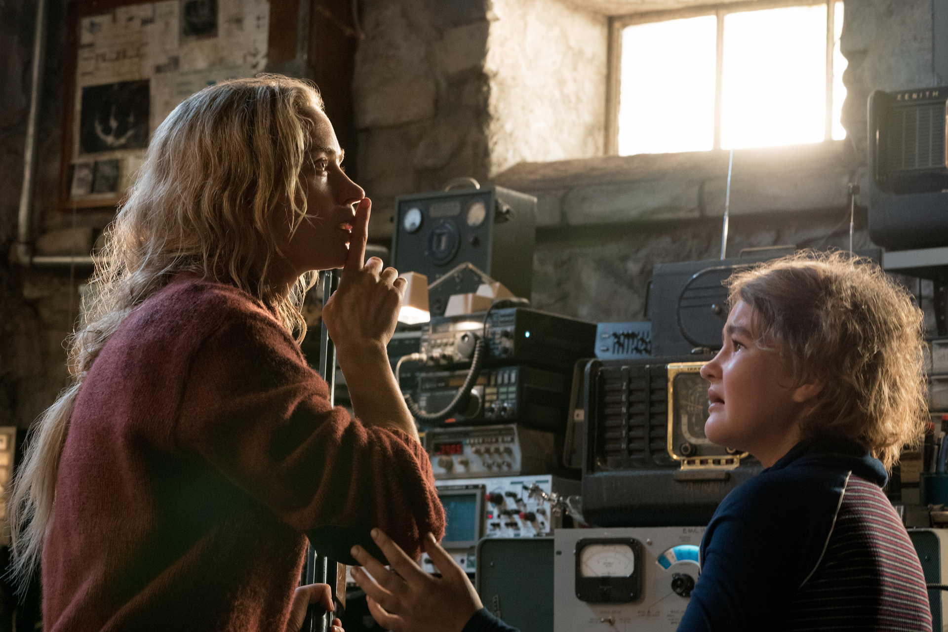 "A Quiet Place": Evelyn (Emily Blunt) hält ihren Zeigefinder an die Lippen. Ihre Tochter (Millicent Simmonds) sieht sie verängstigt an. Beide stehen vor diversen Funkgeräten und Empfängern.