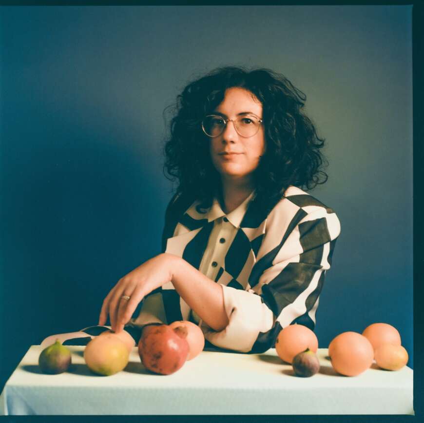 Alexandra Streliski sitzt an einem Tisch mit Obst und Gemüse.