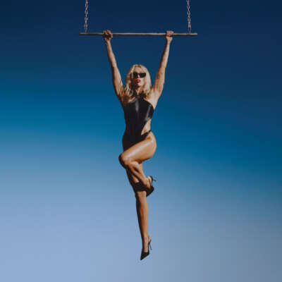 Miley Cyrus hält sich an einer Schaukel fest und hängt in der Luft.