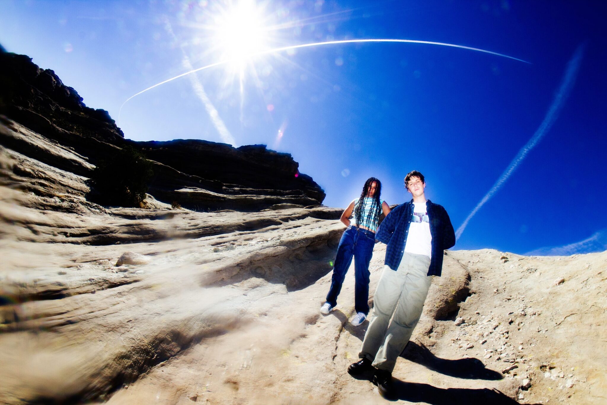 Diva-Sachy Jeffrey und Alex Headford alias Jadu Heart stehen in einer weiten Landschaft und die Sonne glüht am Himmel.