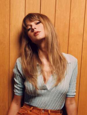 Taylor Swift lehnt an einer Holzverkleidung.