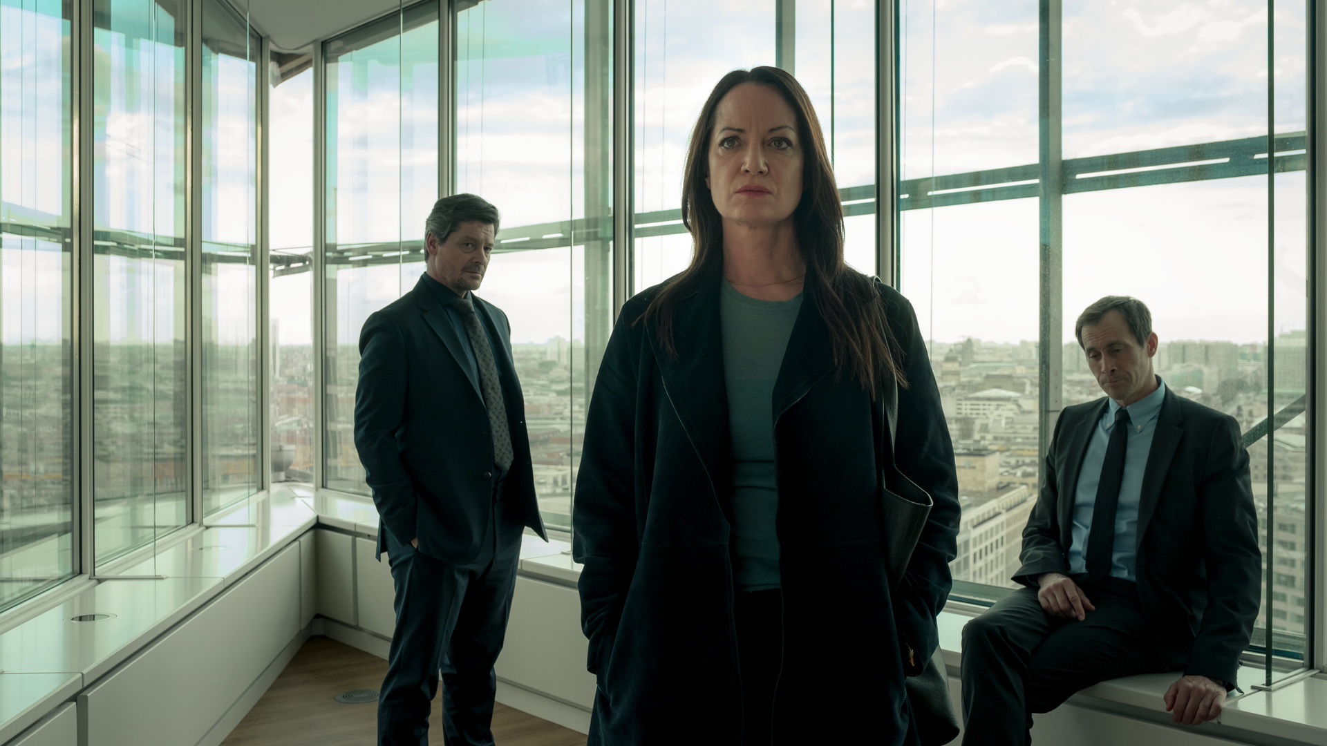 "Wahrheit oder Lüge": Annabelle (Natalia Wörner) steht in einem Büro und schaut in die Ferne. Hinter ihr befindet sich John (Fritz Karl), der sie ansieht. Tom (Marc Hosemann) sitzt auf der Fensterbank und starrt unter sich.