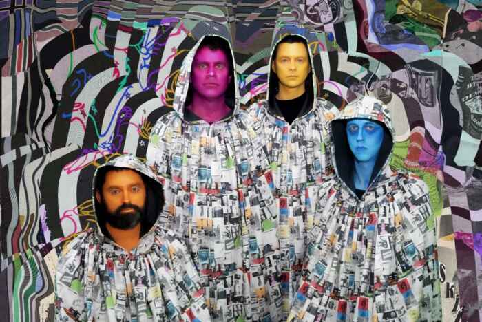 Die Mitglieder von Animal Collective stehen in bunten Mänteln vor einem psychedelischem Hintergrund und haben ihre Gesichter bunt angemalt.