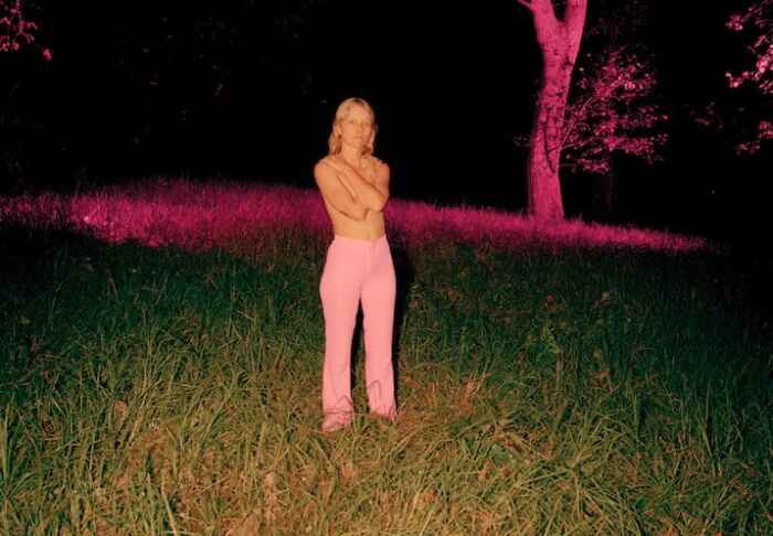 Alice Phoebe Lou auf einer Wiese, vor einem dunklen Hintergrund.