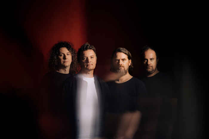 Die vier Mitglieder von Madsen, vor einem rötlich schwarzen Hintergrund.