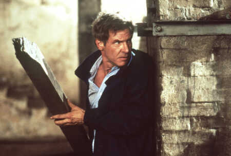 "Das Kartell": Jack Ryan (Harrison Ford) in Nahaufnahme. Er steht in Verteidigungshaltung an einer Hausecke und hält eine Holzlatte in den Händen - bereit zum Schlag.