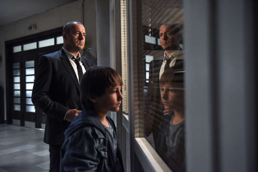 "Die verschwundene Familie (1)": Tom (Timo Hack) und Kessler (Heino Ferch) stehen vor einem Fenster mit heruntergelassenen Jalousien und schauen hinein.