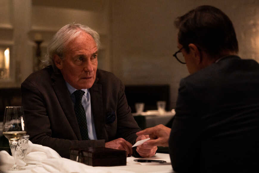 "Requiem für einen Freund": Sebastian Marquardt (August Zirner) sitzt Joachim Vernau (Jan Josef Liefers) an einem Tisch in einem Restaurant gegenüber und schaut diesem in die Augen. Er hält eine weiße Karte in der Hand.