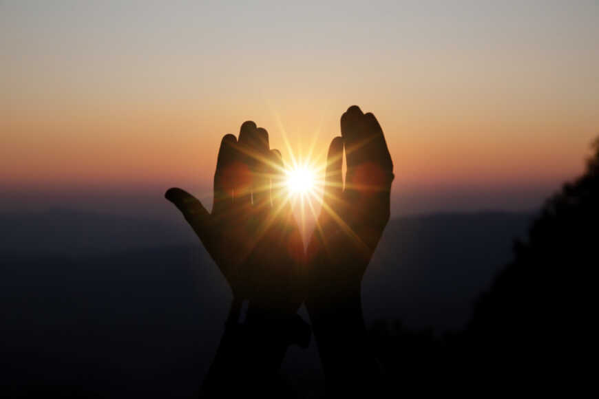 das-geistige-gebet-ueberreicht-sonnenschein-mit-unscharfem-schoenen-sonnenuntergang