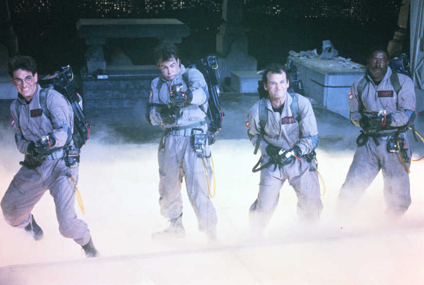 "Ghostbusters": Dr. Egon Spengler (Harold Ramis), Dr. Raymond Stantz (Dan Aykroyd), Dr. Peter Venkman (Bill Murray) und Winston Zeddmore (Ernie Hudson) stehen in Geisterjägerausrüstung nebeneinander und kämpfen.