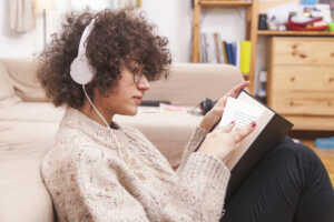 side-view-teenager-reading-book-listening-music