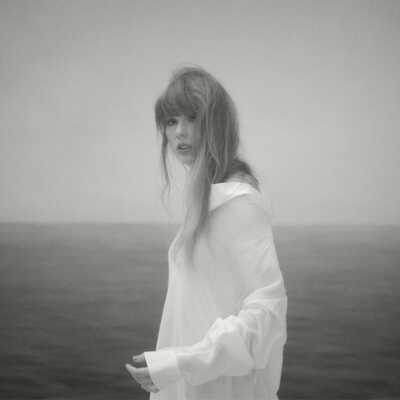 Presseshot von Taylor Swift, schwarz-weißes Foto, auf dem die Sängerin vor einem Meer oder See zu sehen ist.