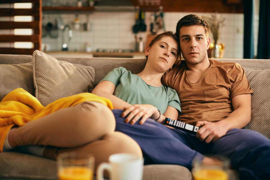 young-embraced-couple-watching-tv-while-relaxing-sofa