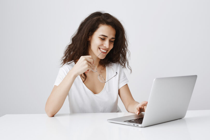 cheerful-woman-smiling-pleased-laptop-while-sit-desk