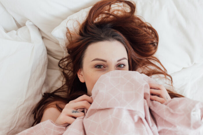 pretty-lovely-young-woman-peeks-out-bedsheets-covers