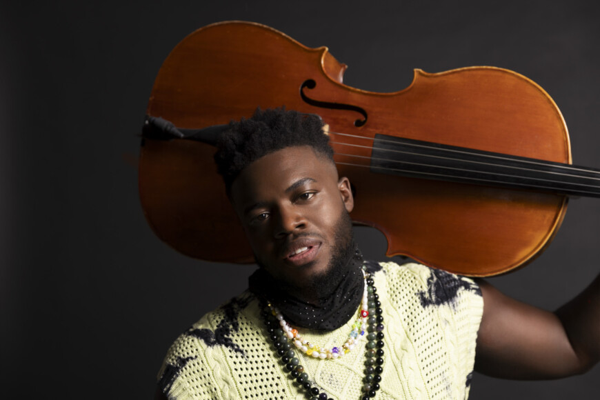 Künstler Kevin Olusola mit Cello auf der Schulter.