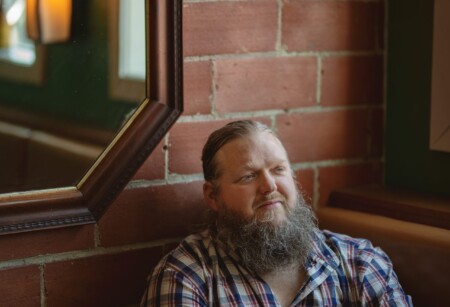 Matt Andersen sitzt vor einer Backsteinwand und sieht zufrieden aus.