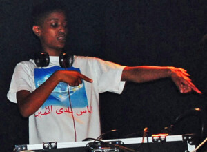 Syd am tanzen vor einem DJ Pult, um ihren Nacken Kopfhörer.