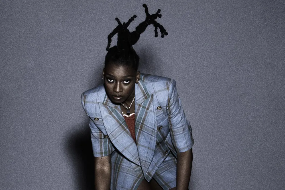 Rapperin Little Simz posiert im Anzug für die Kamera.