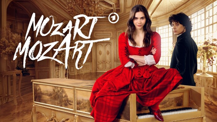 Maria Anna (Havana Joy) und Wolfgang Amadeus (Eren M. Güvercin) Mozart lehnen an einem Klavier in einem großen Saal. „Mozart/Mozart“ läuft im Ersten und kann in der ARD-Mediathek gestramt werden.