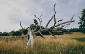 Avalon Emerson steht in der Natur auf einem weiten Feld und lässt einen Greifvogel von ihrem Arm in die Luft aufsteigen.