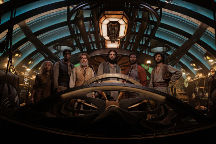 "Nautilus - Anahata": Suyin (Ling Cooper Tang), Ranbir (Ashan Kumar), Benoit (Thierry Frémont), Nemo (Shazad Latif), Boniface (Pacharo Mzembe) und Turan (Arlo Green) stehen nebeneinander im Innern eines U-Boots hinter einem großen Steuerrad.