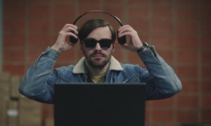 Roman Mertens (Bart Kelchtermans) sitzt in einem Raum vor einem aufgeklappten Laptop. Er trägt eine dunkle Brille und setzt sich gerade Kopfhörer auf. Roman Mertens (Bart Kelchtermans) beginnt bei der rotterdamer Polizei zu arbeiten und hilft ihnen Abhöraufnahmen zu analysieren. „Blind Sherlock“ läuft im Zweiten und kann in der ZDF-Mediathek gestreamt werden.