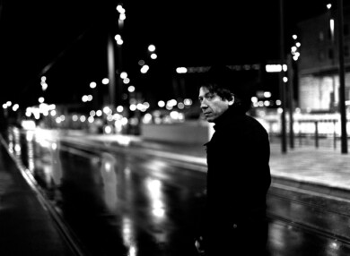 Michael Morvek läuft im Dunkeln über eine Straße, die von Laternen beleuchtet wird und blickt in die Kamera.