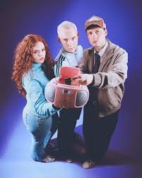 Inspector Spacetime: zwei junge Männer und eine junge Frau mit roten Locken halten zu dritt einen roten CD-Player in die Kamera.