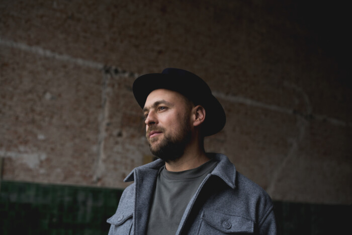 Max Mutzke trägt eine graue Jacke und einen der schwarzen Hüte, die für ihn charakteristisch sind.