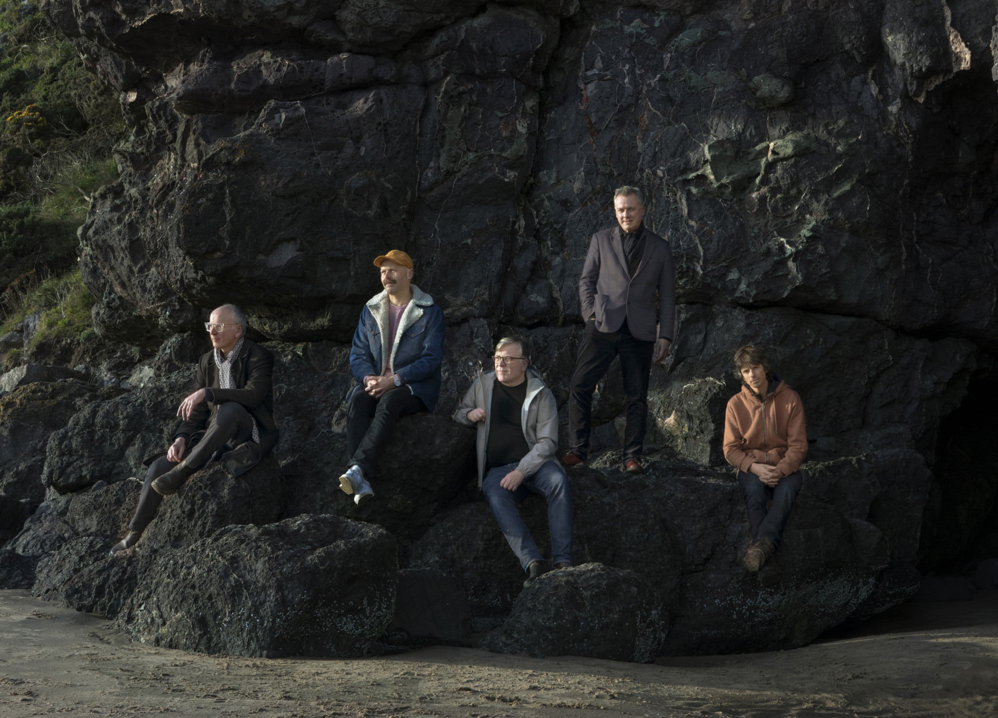 Die Mitglieder von Teenage Fanclub sitzen auf einem Felsen
