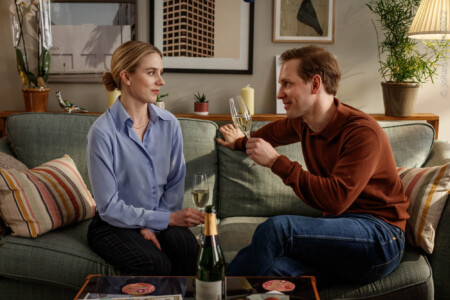 Mathilda (Carla Sehn) und Johannes (Simon Reithner) sitzen sekttrinkend auf der Couch