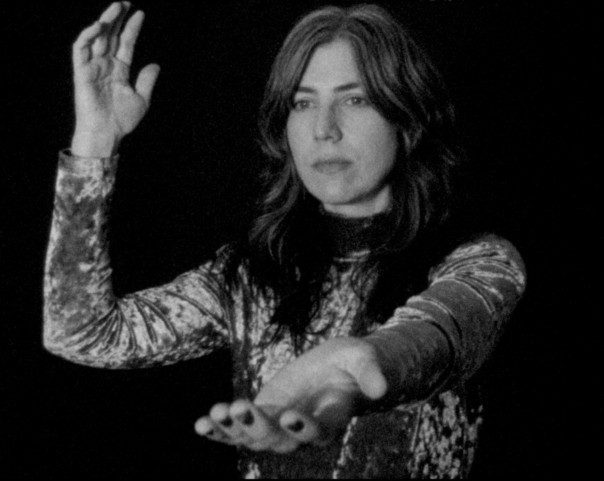 Julia Holter steht mit ausgestreckten Armen auf einem verträumten schwarz-weiß Bild.