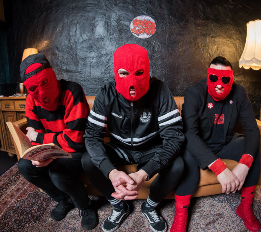 Die Mitglieder von SOKO LiNX sitzen in roten Sturmmasken nebeneinander auf einem Sofa.